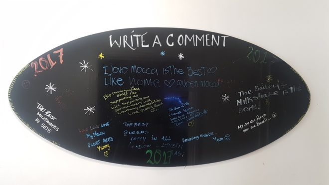 An oval chalkboard on the wall covered in customers' handwritten messages