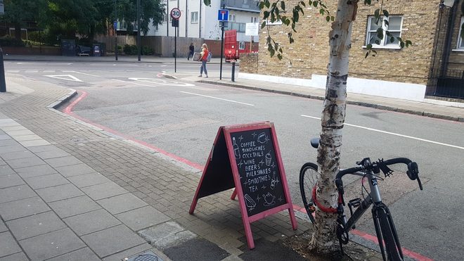 The street corner outside with a chalk A-board and a bike chained to a tree