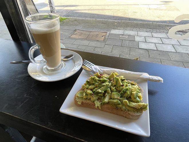 Latte and avocado toast on the window-side table with the street behind