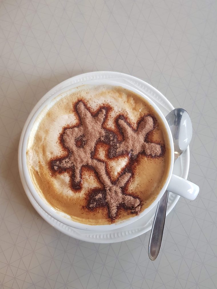 A cappuccino with a stencilled chocolate pattern on the foam, shot from overhead