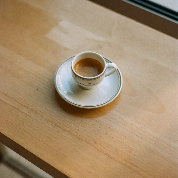 An espresso in a small white cup on a saucer