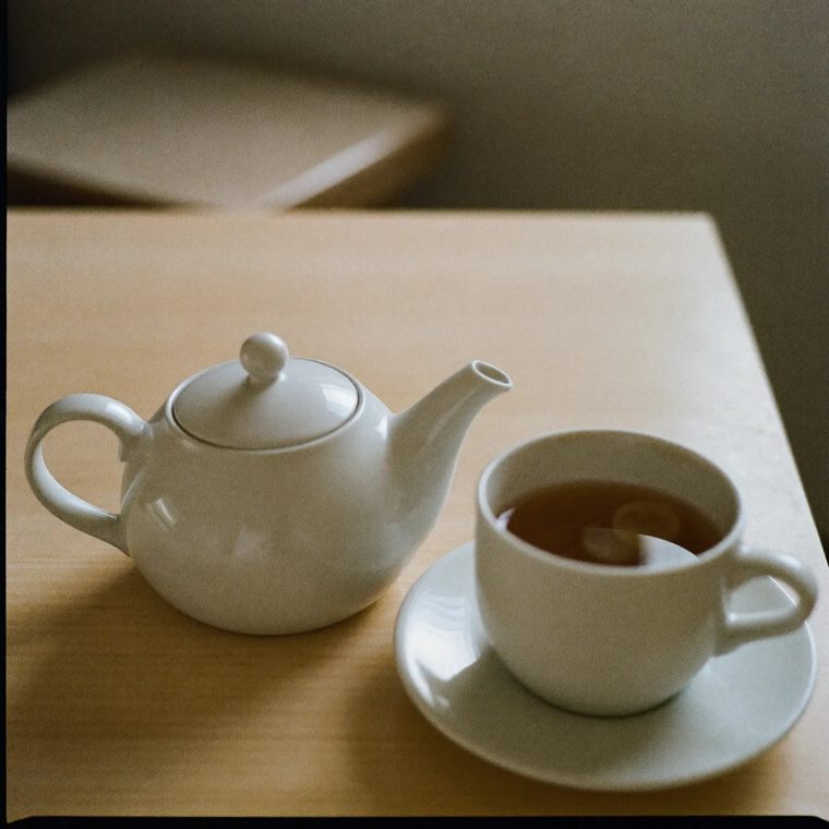 A pot of tea with a white cup beside it
