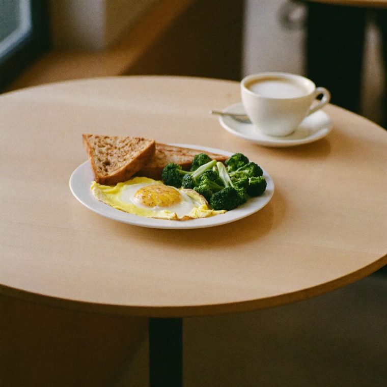 A poached egg plate beside a cup of coffee